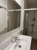 Detalle del lavabo del Apartamento Exterior sobre un mueble de madera con cajones y pared de azulejos blancos